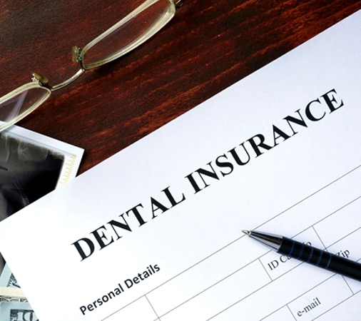 A piece of paper that reads “Dental Insurance” along with a pair of glasses, X-ray, money, and a pen