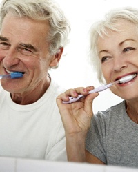 Happy senior couple brushing teeth to care for dental implants