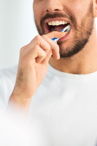 Man caring for dental implants by brushing teeth