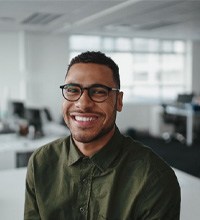 a man smiling and sitting on a desk