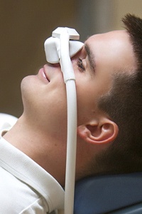 A young man preparing for a dental procedure and wearing a nasal mask to receive nitrous oxide