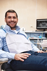 A middle-aged man seated in a dentist’s chair waiting for the professional to come in and begin administering sedation